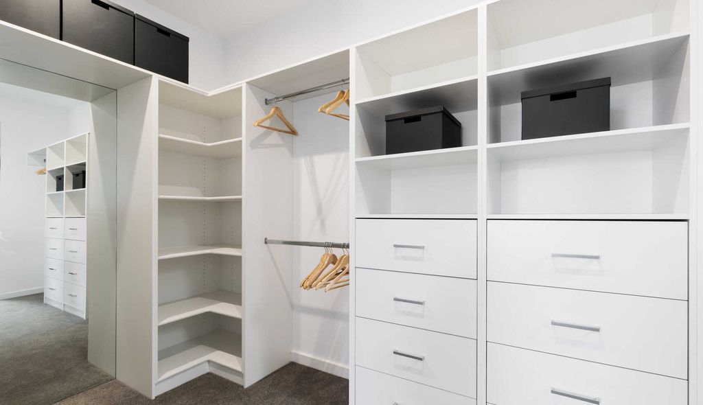 Ein weißer begehbarer Kleiderschrank mit Schubladen und Regalen